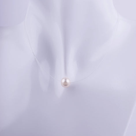 Collar de perla blanca natural suspendida en un hilo transparente invisible, estilo gargantilla minimalista sobre busto de exhibición.