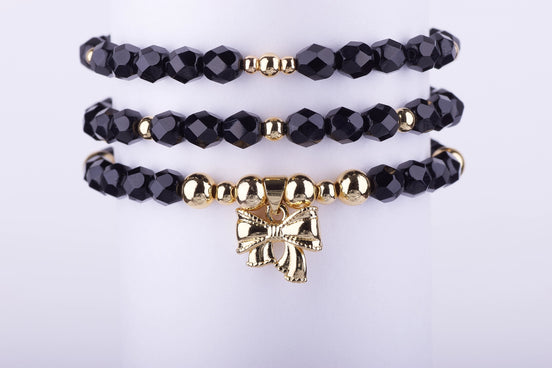 Set de 3 Pulseras de Cuentas de Cristal Negro Azabache y charm de Lazo en Oro Laminado. Elegancia atemporal y envío rápido.