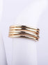Anillo ancho dorado compuesto por varias bandas finas entrelazadas con acabado brillante sobre fondo blanco.