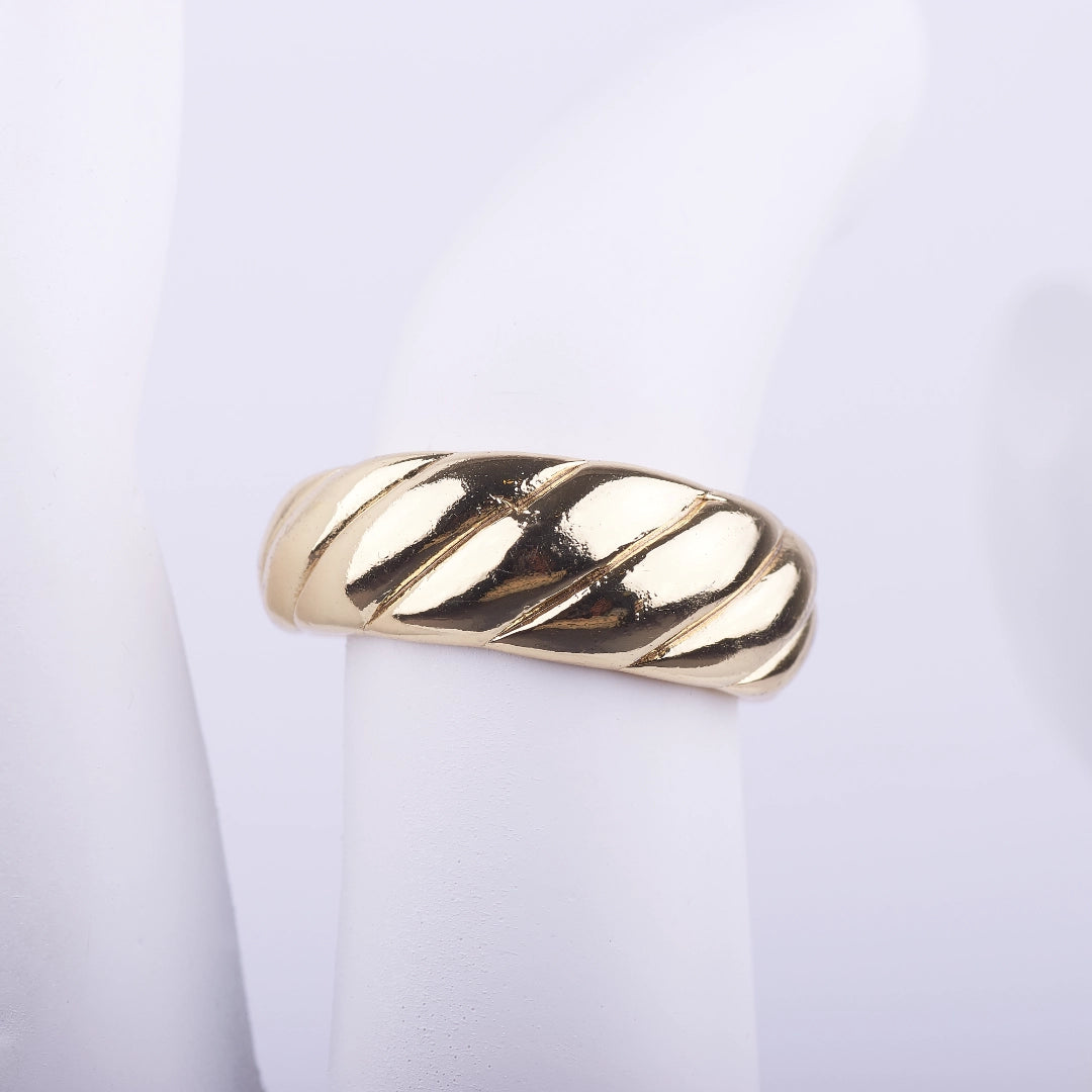 Anillo ancho dorado con textura de líneas diagonales en relieve tipo croissant sobre fondo blanco.