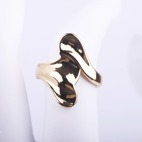 Anillo ancho dorado de diseño fluido y orgánico con acabado brillante tipo espejo sobre fondo blanco.