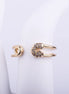 Anillo abierto con forma de imperdible dorado y detalles de cristales brillantes en la punta, sobre fondo blanco.
