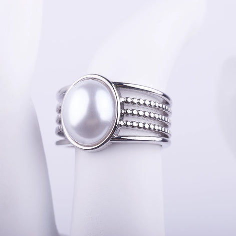 Anillo ancho plateado con una gran perla central y banda decorativa de cinco niveles lisos y de cuentas sobre fondo blanco.