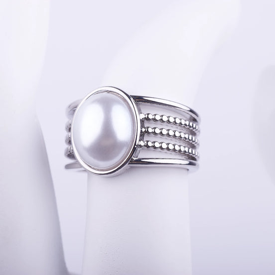 Anillo ancho plateado con una gran perla central y banda decorativa de cinco niveles lisos y de cuentas sobre fondo blanco.