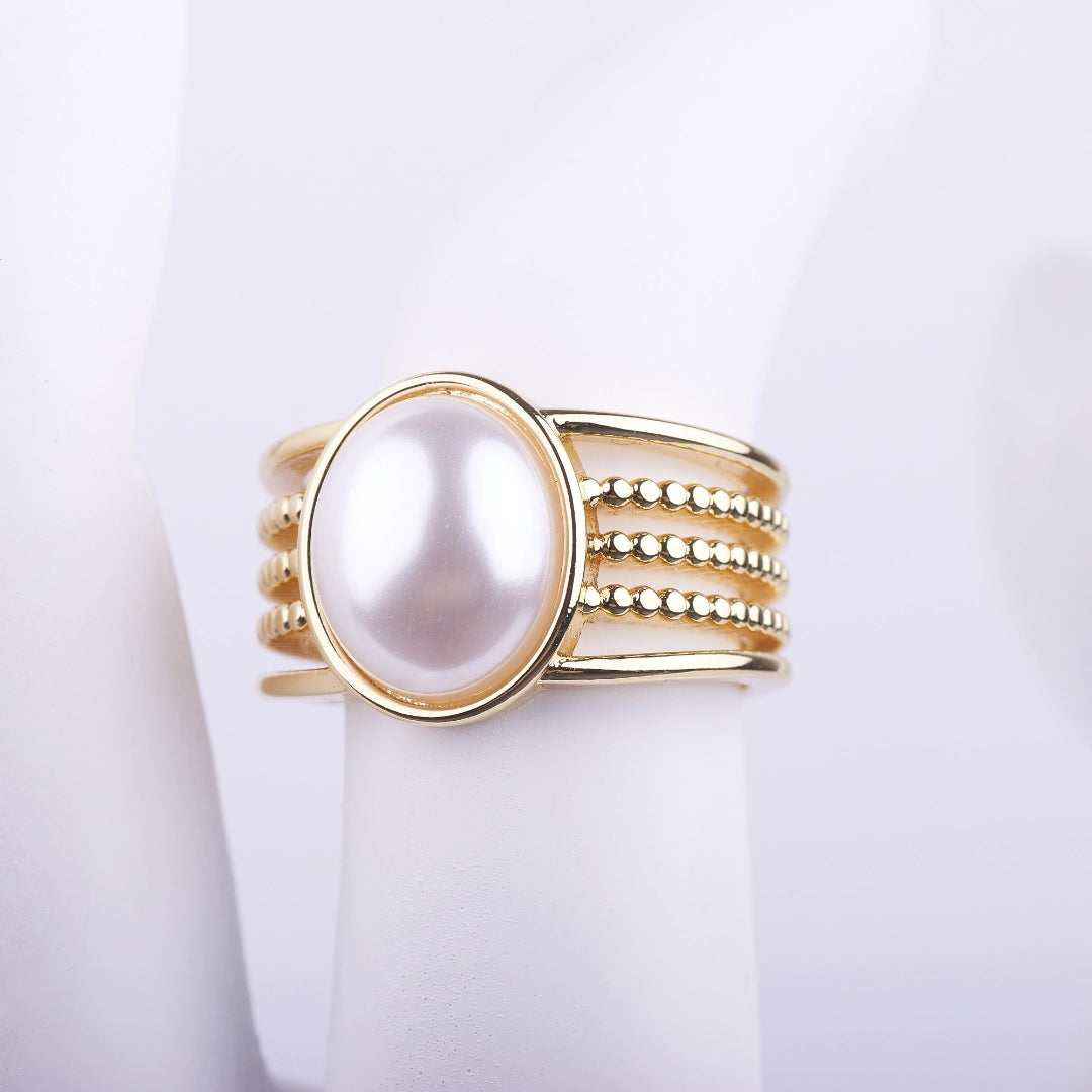 Anillo ancho dorado con una gran perla blanca central y banda de múltiples filas lisas y de cuentas sobre fondo blanco