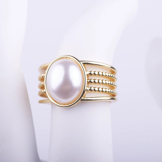 Anillo ancho dorado con una gran perla blanca central y banda de múltiples filas lisas y de cuentas sobre fondo blanco