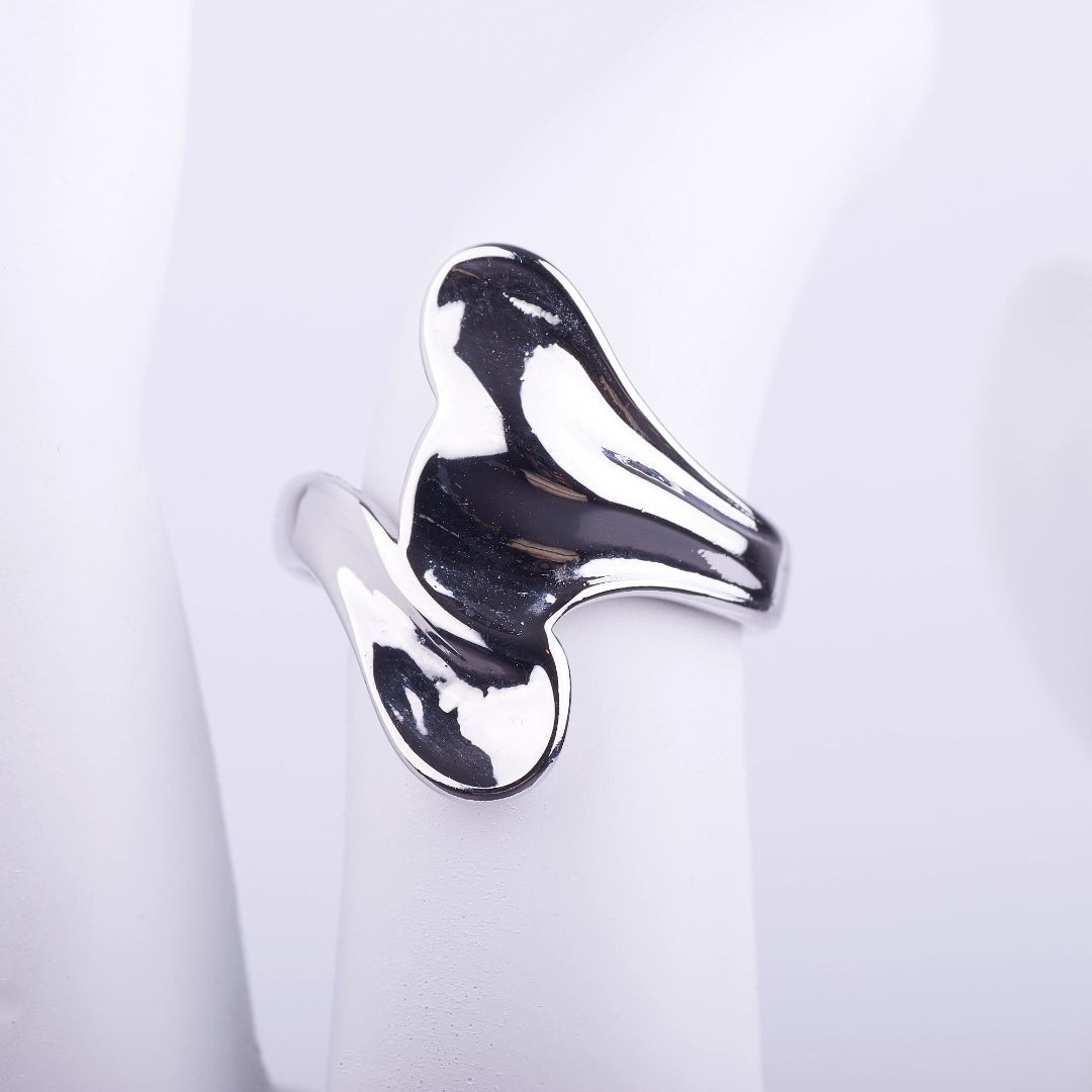 Anillo ancho plateado de forma irregular y fluida con acabado brillante tipo espejo sobre fondo blanco.