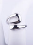 Anillo abierto plateado de diseño fluido con forma de gota estilizada y acabado brillante sobre fondo blanco.
