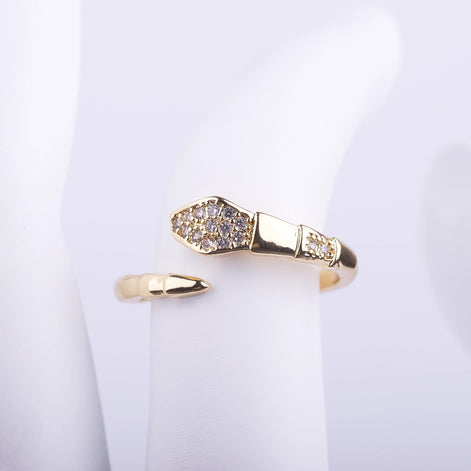Anillo ajustable en forma de serpiente dorada con cabeza incrustada de cristales brillantes sobre fondo blanco.