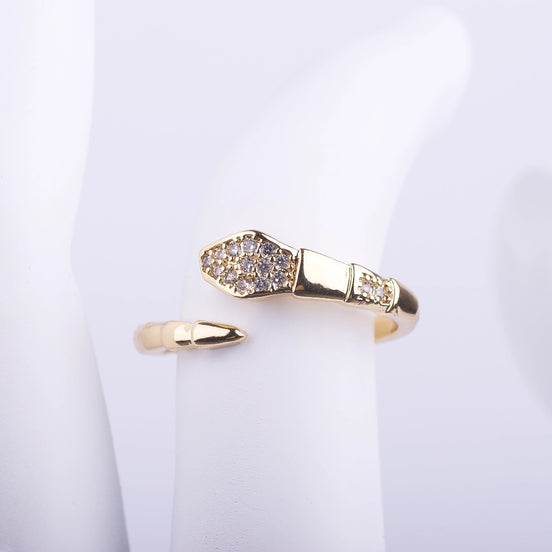Anillo ajustable en forma de serpiente dorada con cabeza incrustada de cristales brillantes sobre fondo blanco.