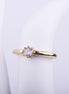 Anillo delgado con acabado dorado y piedra central brillante sobre soporte blanco, estilo minimalista de moda.