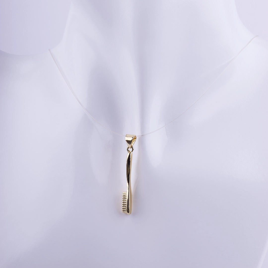 Dije de cepillo de dientes dorado en acabado pulido suspendido en un hilo invisible sobre un busto blanco, joyería temática para dentistas.