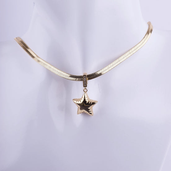 Collar de cadena plana tipo serpiente (herringbone) bañada en oro, con dije de estrella voluminosa y detalles de zirconia. Joyería de alta moda.