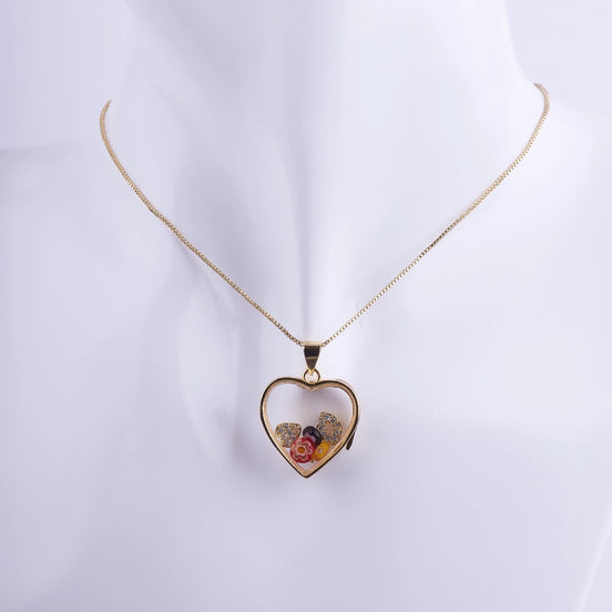 Collar de corazón tipo relicario flotante con marco bañado en oro, flores minúsculas encapsuladas, y detalles de zirconias. Joyería romántica para regalo.