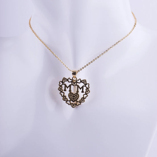 Collar con dije de corazón de filigrana bañado en oro, la palabra MAMÁ en el centro y micro zirconias. Regalo perfecto para el Día de la Madre.