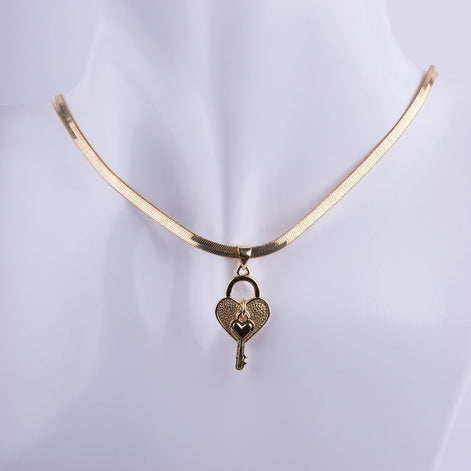 Gargantilla collar dorada de cadena plana con dije de llave y candado en forma de corazón, joyería elegante y moderna sobre fondo blanco.