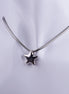 Collar plateado con dije de estrella en 3D y cadena tipo serpiente sobre maniquí blanco, joyería de acero inoxidable estilo moderno.