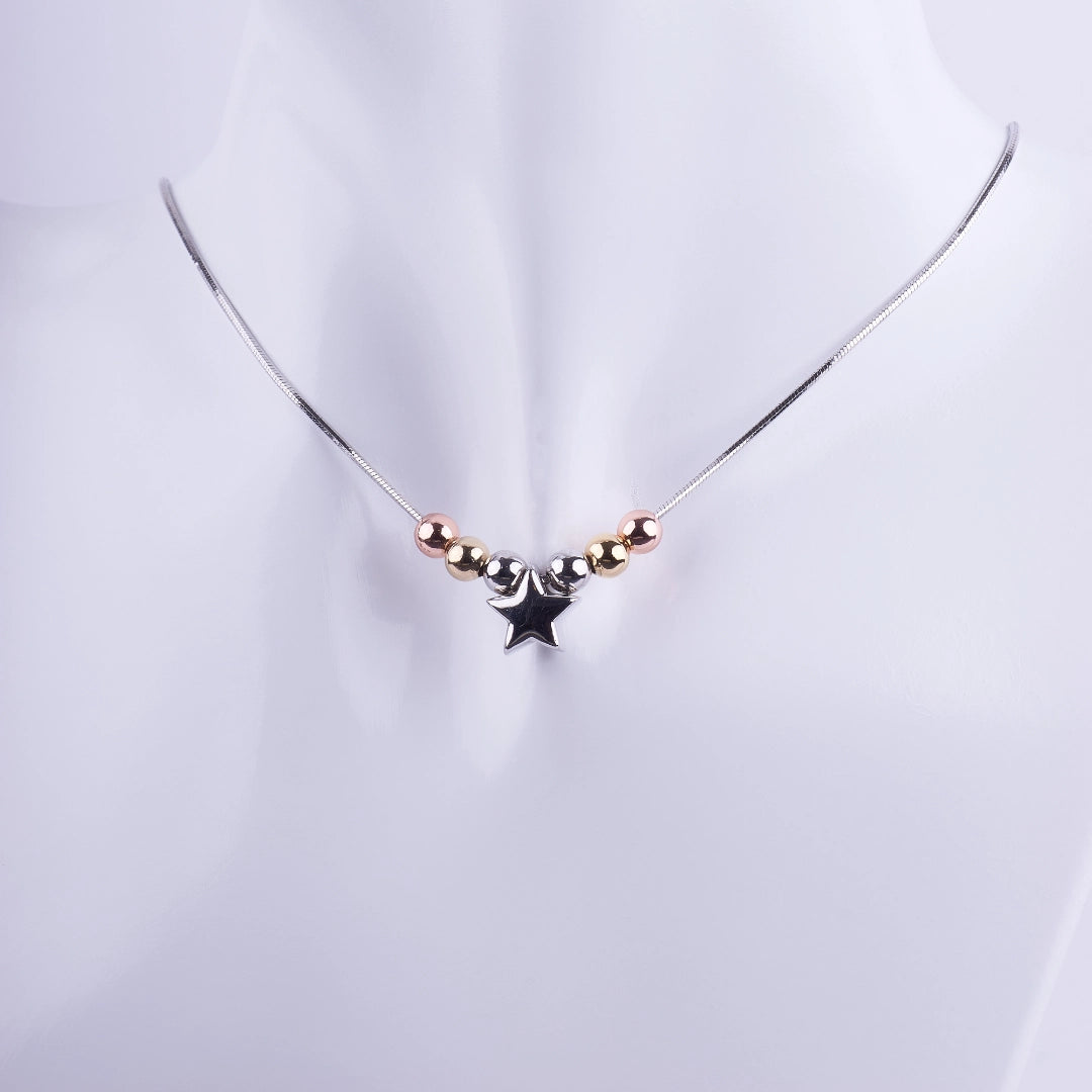 Collar minimalista con un dije de estrella plateada y cuentas en tonos oro, plata y oro rosa sobre una cadena de serpiente fina.