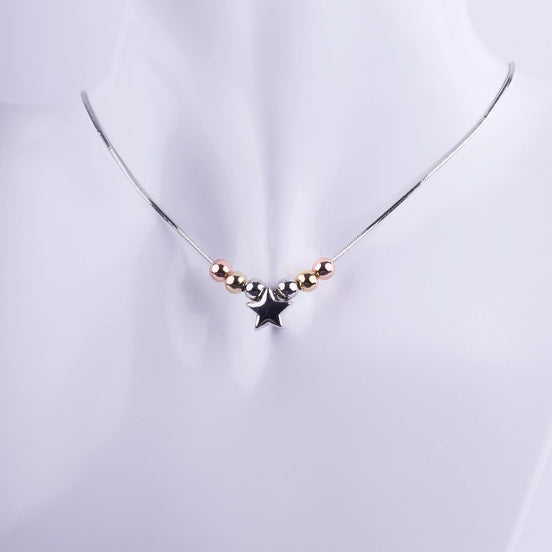 Collar minimalista con un dije de estrella plateada y cuentas en tonos oro, plata y oro rosa sobre una cadena de serpiente fina.