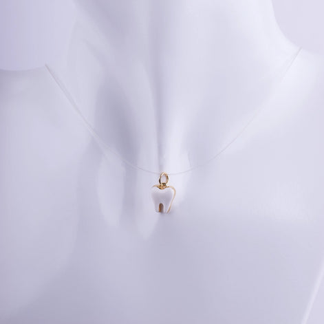 Colgante en forma de muela con esmalte blanco y bordes dorados en hilo invisible, joyería profesional para especialistas dentales.