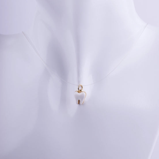 Colgante en forma de muela con esmalte blanco y bordes dorados en hilo invisible, joyería profesional para especialistas dentales.