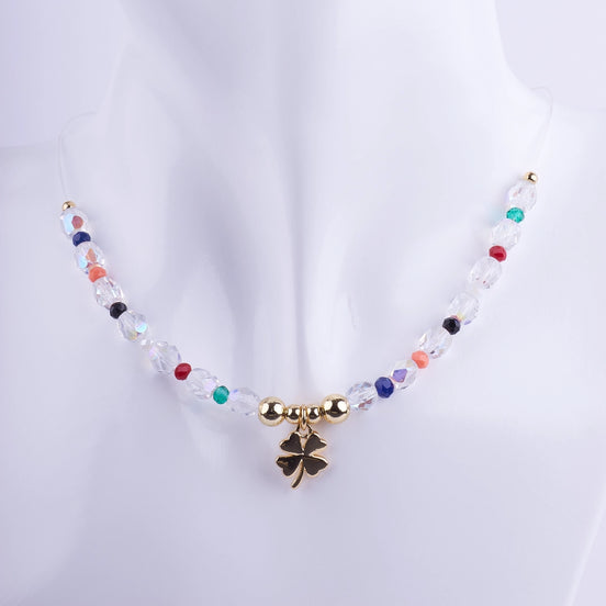 Collar gargantilla de hilo transparente con dije de trébol de cuatro hojas bañado en oro, rodeado de cuentas de cristal facetado transparente y multicolor (arcoíris).