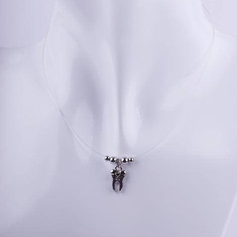 Collar de hilo invisible con dije de muela plateada y pequeñas esferas de metal, joyería temática para profesionales de la odontología.