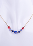 Collar de cadenilla dorada con nueve cuentas de cristal de Murano de colores rojo y azul, exhibido en un busto blanco. El detalle central es una cuenta azul con diseño de flor roja y blanca.