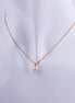 Collar minimalista con una perla natural color melocotón colgando de una cadena veneciana bañada en oro sobre un busto de exhibición.