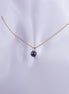 Collar minimalista con una perla negra solitaria colgando de una cadena veneciana bañada en oro sobre un fondo blanco.
