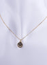 Collar bañado en oro con dije circular de carita feliz (smiley face) con ojos de zirconias brillantes sobre cadena veneciana.
