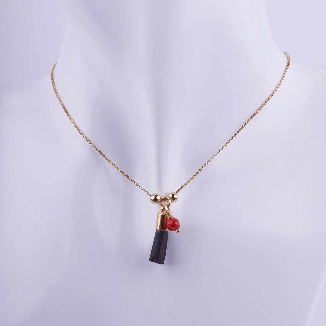 Collar Cadena Fina Dorada con Colgante de Turmalina Negra Bruta y Coral Rojo en maniquí blanco. Joyería de protección minimalista.