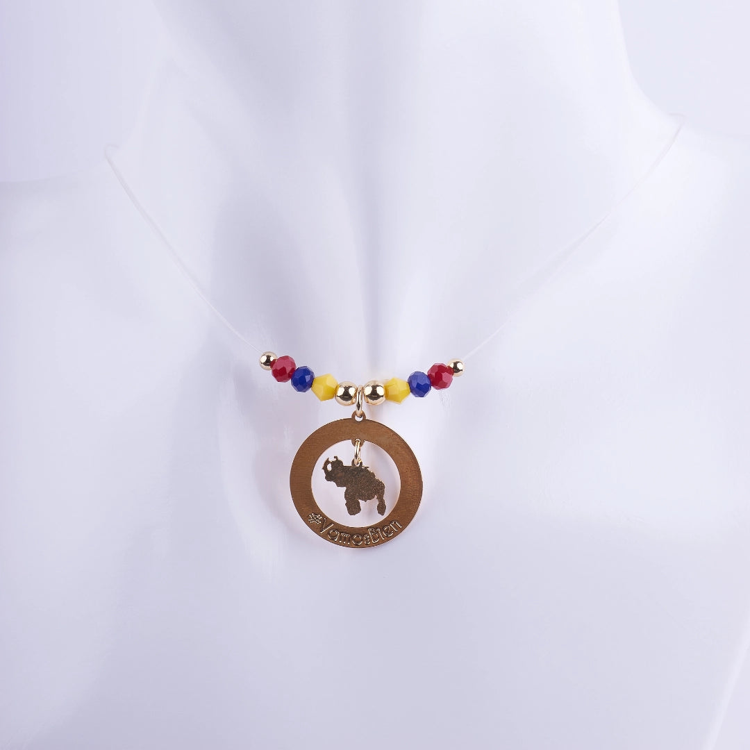 Collar Mi Patria Querida de hilo transparente con dije circular dorado, silueta del mapa y cuentas de cristal en amarillo, azul y rojo (bandera de Venezuela).