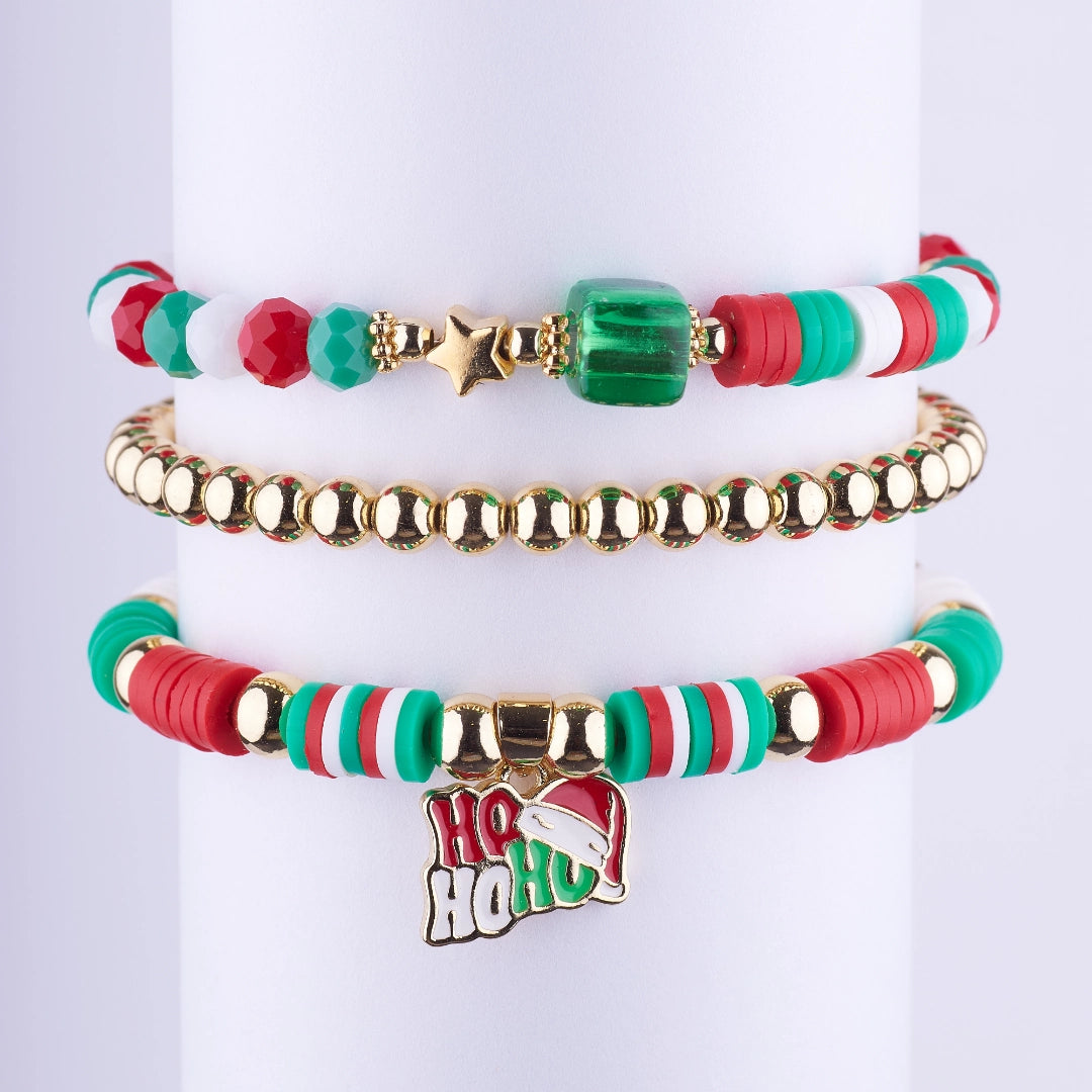Set de 3 pulseras navideñas estilo stacking con cuentas rojas, verdes y blancas, cuentas doradas y dije de Ho Ho Ho. Joyería para fiestas de fin de año.