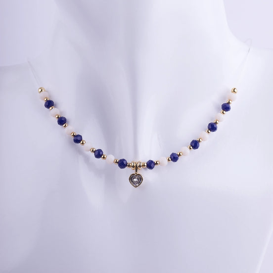 Gargantilla de cuentas facetadas en color azul zafiro y blanco nácar con separadores dorados y un dije central de corazón con zirconia. Joyería elegante bañada en oro.