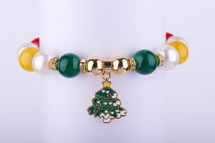 Pulsera elástica con cuentas grandes de colores verde esmeralda, blanco perlado, amarillo y rojo, con un dije esmaltado de árbol de Navidad y espaciadores dorados con cristales.