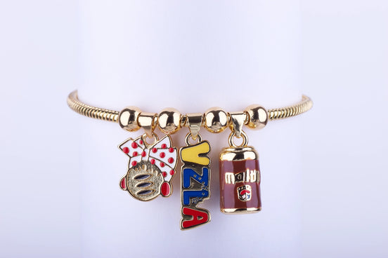 Pulsera de cadena en color oro con tres dijes esmaltados: lazo rojo con lunares, logo de Harina P.A.N. (Arepa) y lata de bebida Maltín Polar de Venezuela