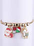 Pulsera dorada con tres dijes esmaltados colgantes: Papá Noel (Santa Claus), saludo Ho Ho Ho con gorro, y reno (ciervo) con puntos.