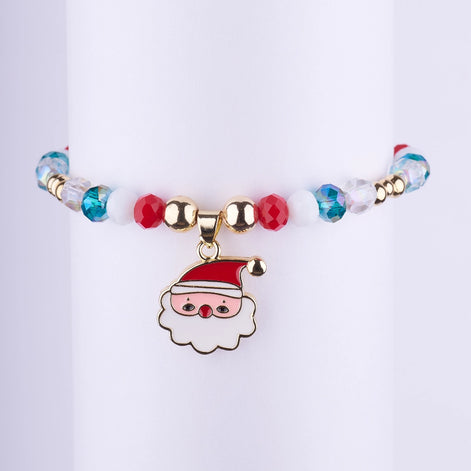 Pulsera elástica de cuentas facetadas en colores rojo, blanco y azul iridiscente, con un dije central de Santa Claus esmaltado en blanco y rojo. Joyería navideña de estilo bohemio.