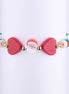 Pulsera navideña con cuentas Heishi rojas, blancas y verdes, con dos dijes grandes de corazón rojo y una cuenta central de la cara de Papá Noel.
