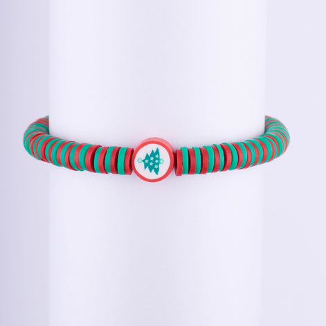 Pulsera navideña minimalista con cuentas de disco (Heishi) rojas y verdes, y una cuenta central con el diseño de un Árbol de Navidad.