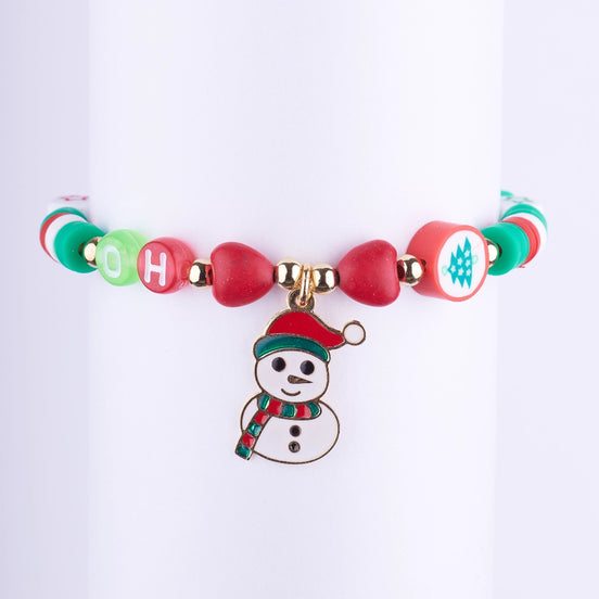 Pulsera navideña con cuentas de disco (Heishi) rojas, blancas y verdes, cuentas de letras, y un dije esmaltado de muñeco de nieve.