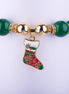 Pulsera elástica con grandes cuentas rojas y verdes, espaciadores dorados con incrustaciones de cristales, y dije de bota navideña esmaltada.