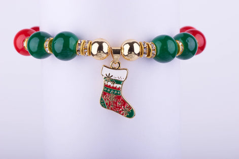 Pulsera elástica con grandes cuentas rojas y verdes, espaciadores dorados con incrustaciones de cristales, y dije de bota navideña esmaltada.