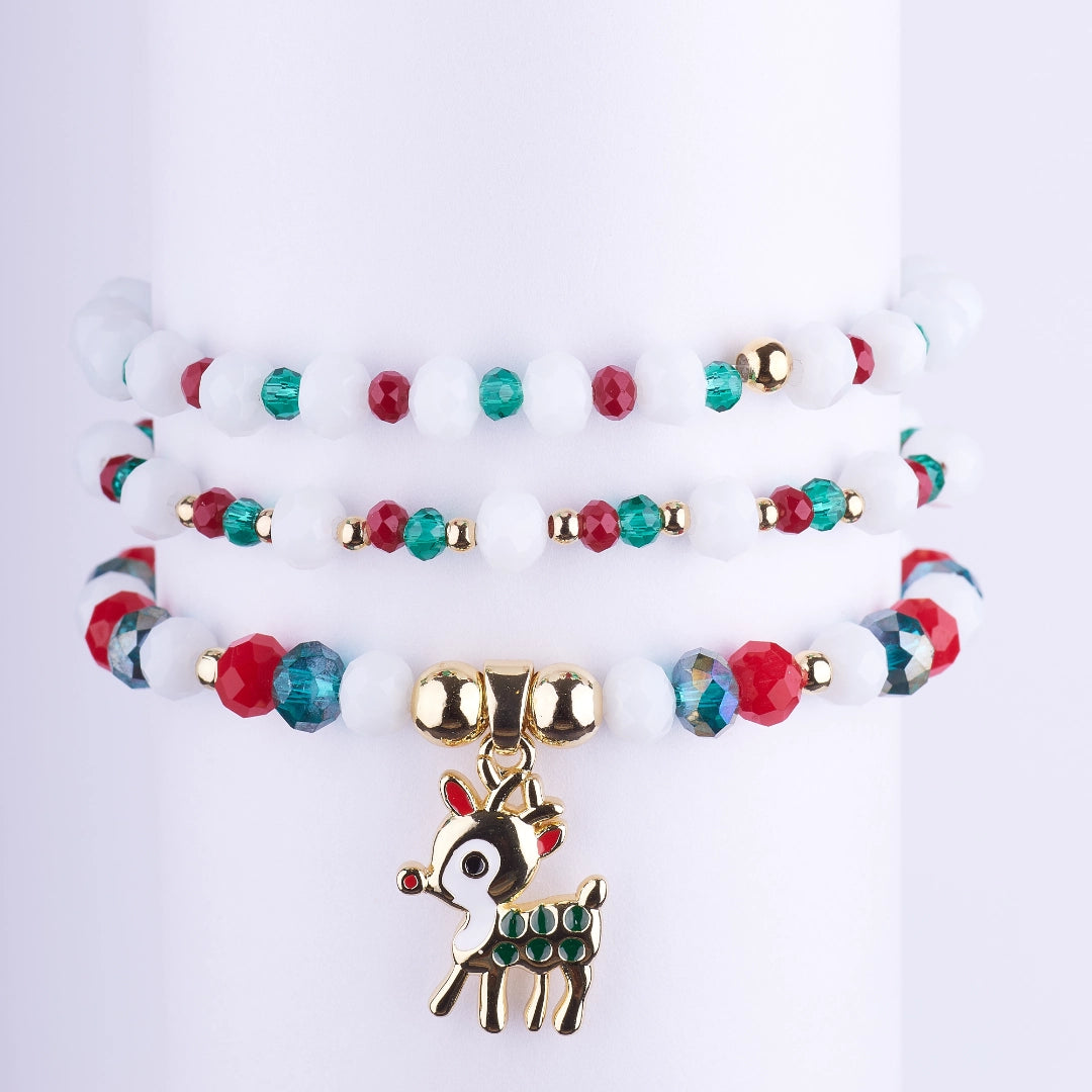 Set de pulseras elásticas navideñas con cuentas de cristal blanco, rojo y verde, y un dije de reno dorado con detalles de pedrería.