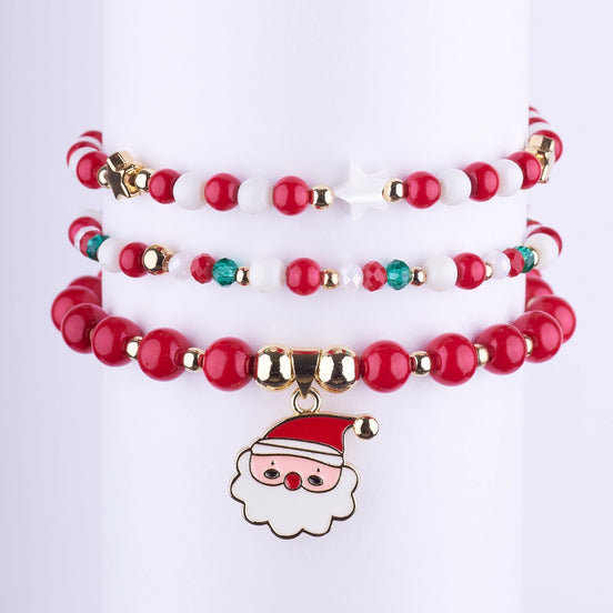 Set de pulseras elásticas navideñas con cuentas opacas rojas y blancas, y un dije esmaltado de Papá Noel dorado.